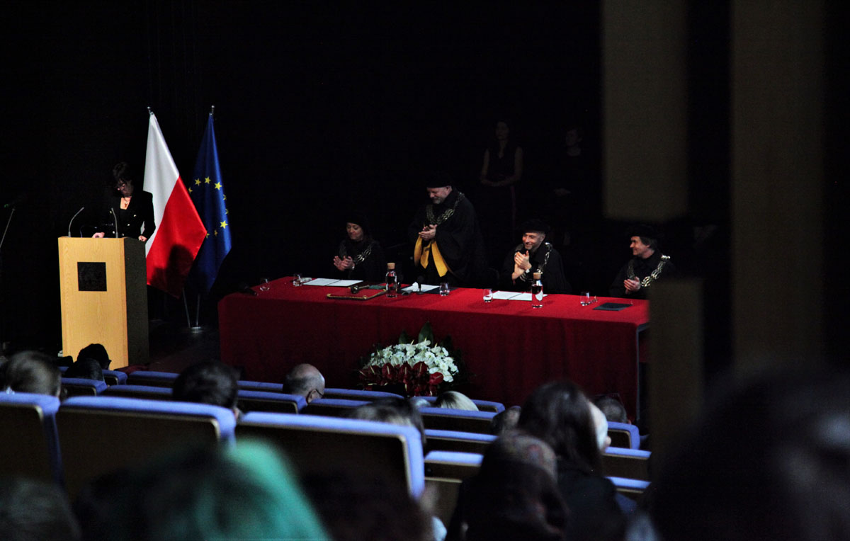 Przedstawiciele władz uczelni za stołem prezydialnym na scenie auli