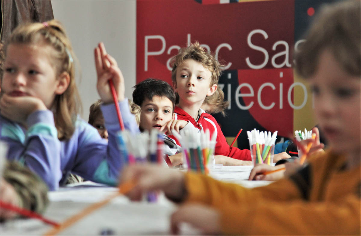 Dzieci przy siedzą przy stole rysunkowym