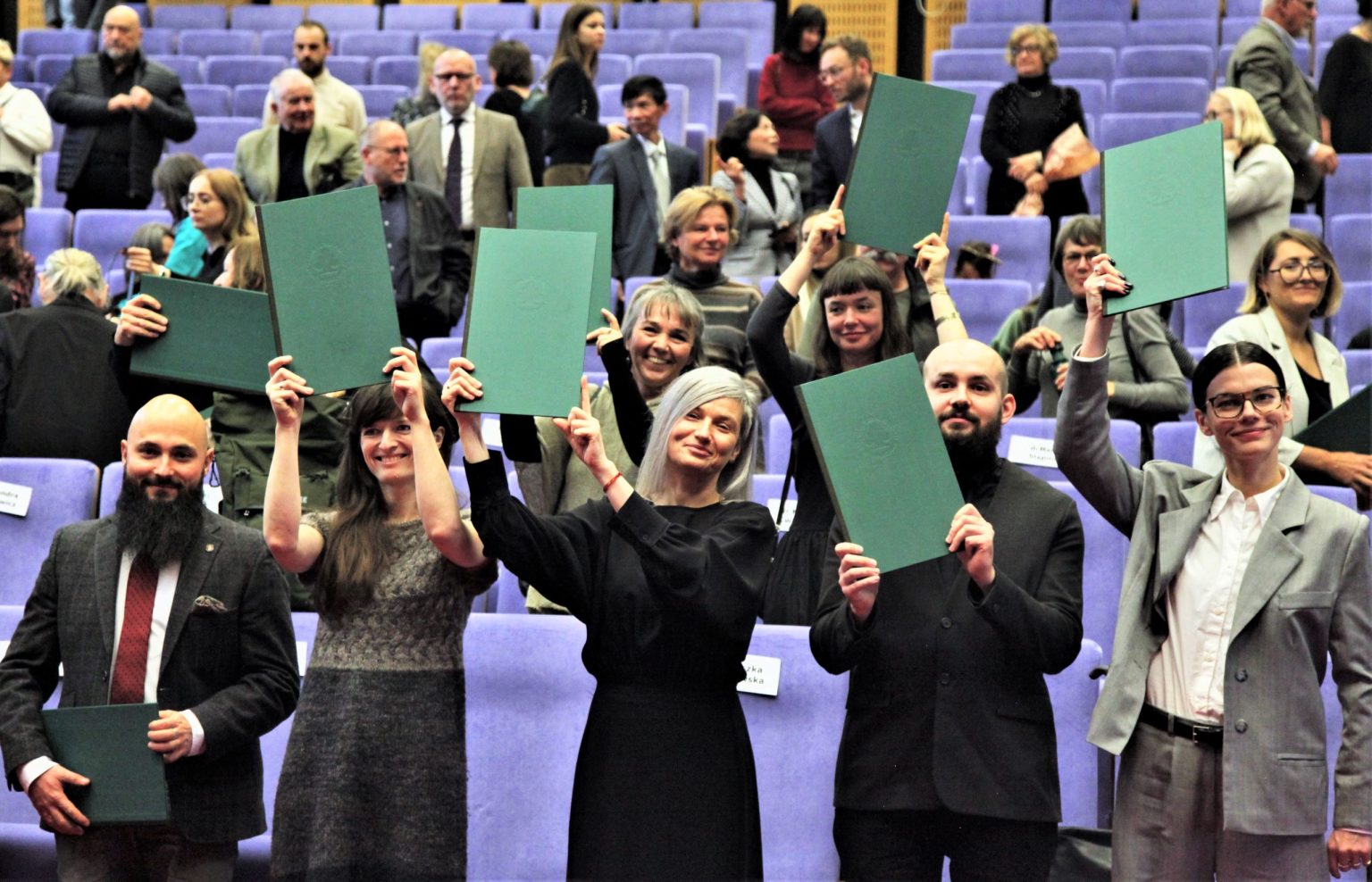Zdjęcie grupowe uczestników ceremonii, trzymających w rękach odebrane dyplomy