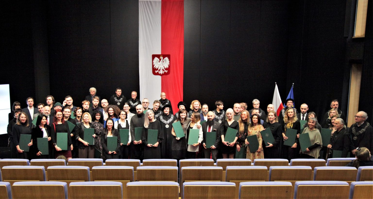 Uczestnicy uroczystości pozują na scenie do zdjęcia grupowego
