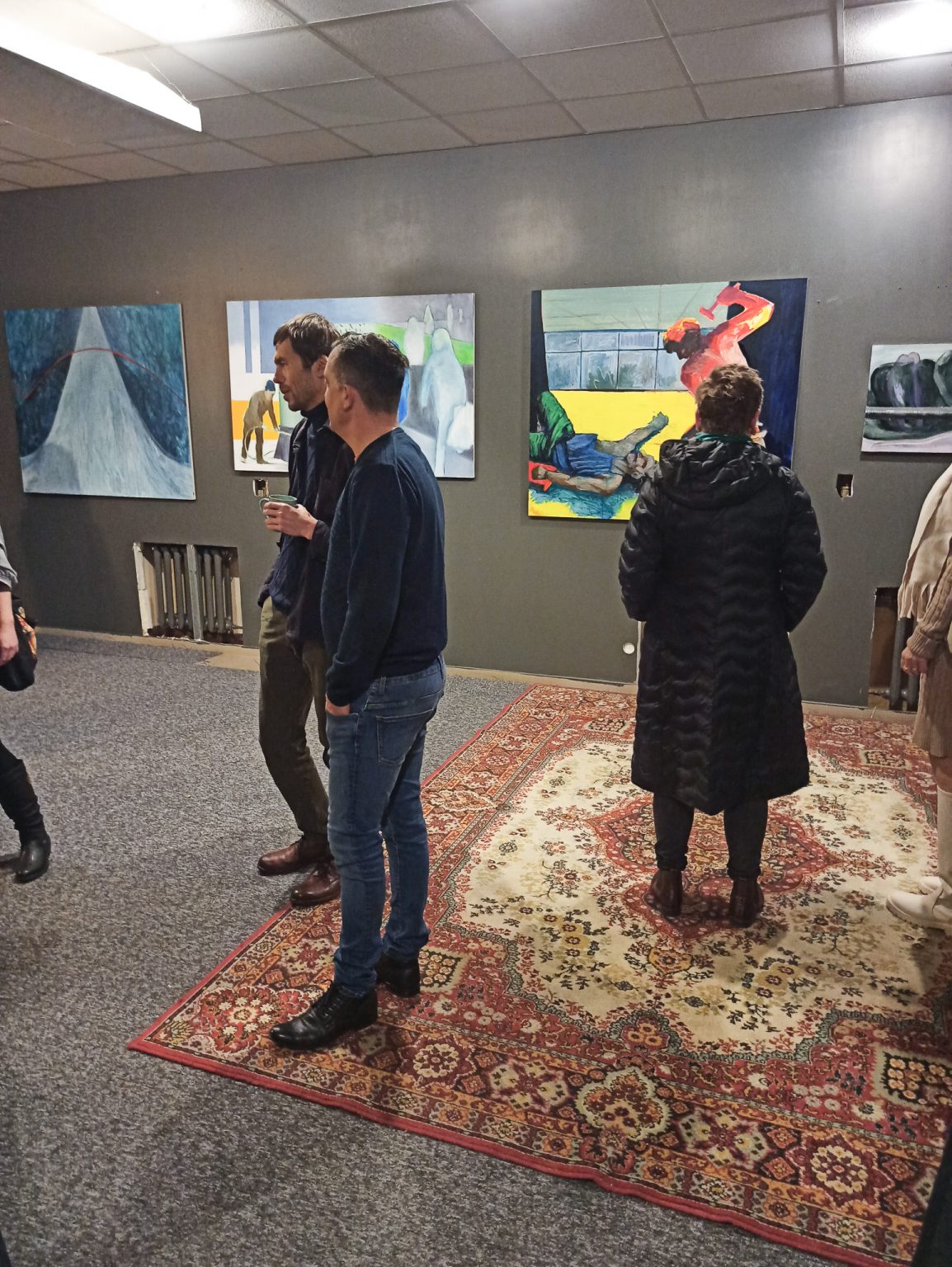 Goście wystawy obserwują zawieszone na ścianach obrazy