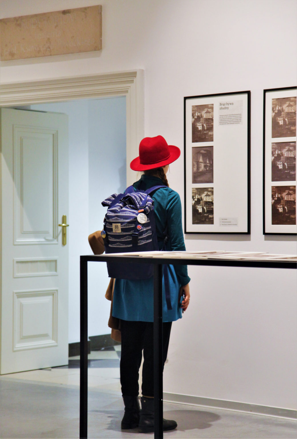 Kobieta w czerwonym kapeluszu przygląda się fotografiom