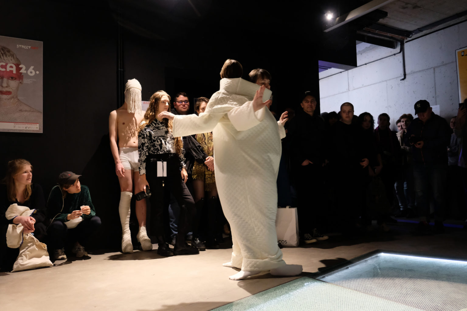 Scena z performance. Dwie osoby ubrane w jeden biały kostium