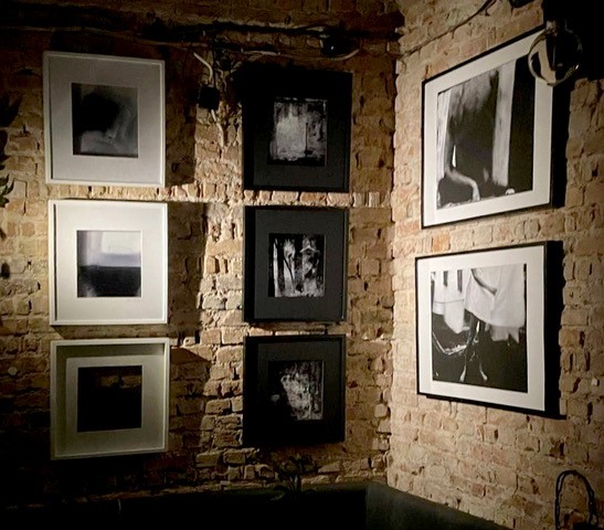 Sala wystawowa. Zjęcia w ramach zawieszone na ceglanym murze