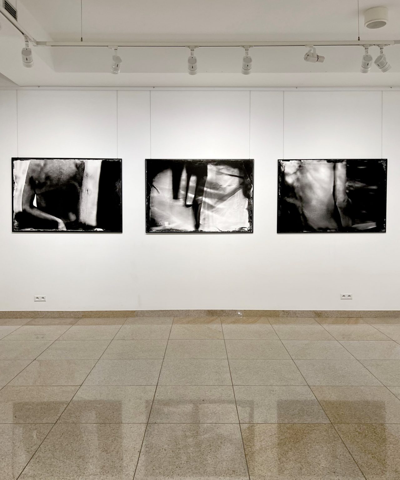 Przestrzeń wystawowa. Na ścianie wiszą oprawione w ramy 3 czarno-białe zdjęcia.