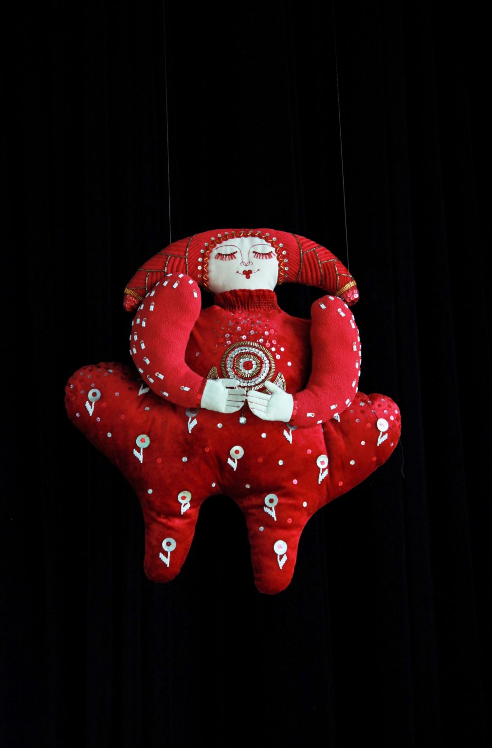 Lalka w kolorze czerwonym z naniesionym folkorystycznymi motywami