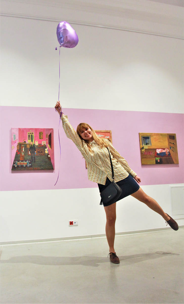 Kobieta stoi na jednej nodze trzymając na sznurku unoszący się nad nią balonik.