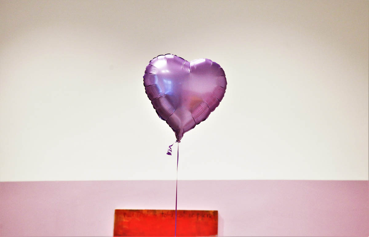 Nadmuchany helem balonik unosi się w sali wystawowej