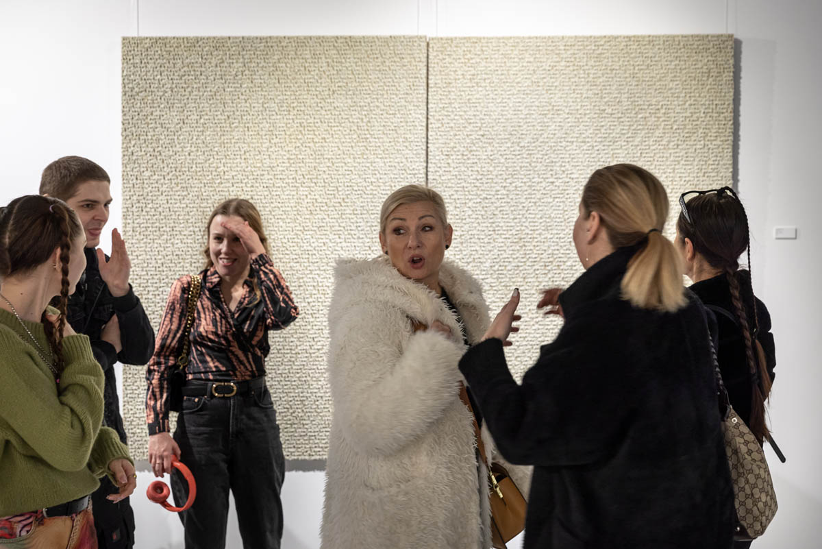 Grupa kobiet - uczestniczek wernisażu w przestrzeni wystawowej.