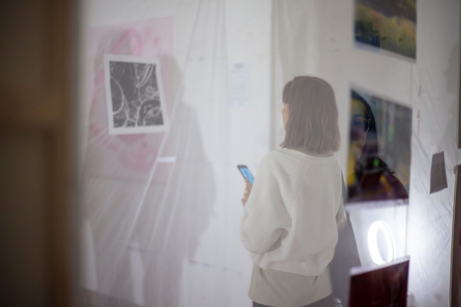 Kobieta przygląda się pracy graficzne zawieszonej na przezroczystym materiale