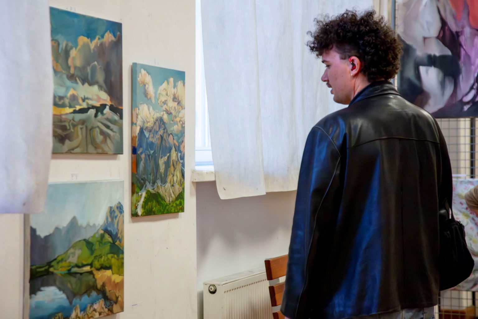 Mężczyzna oglądający zawieszone na ścianie pejzaże