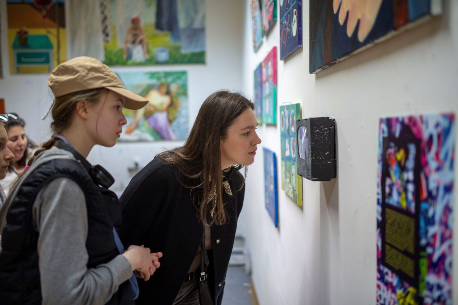 2 kobiety z bliska oglądają prezentowane na ścianie prace