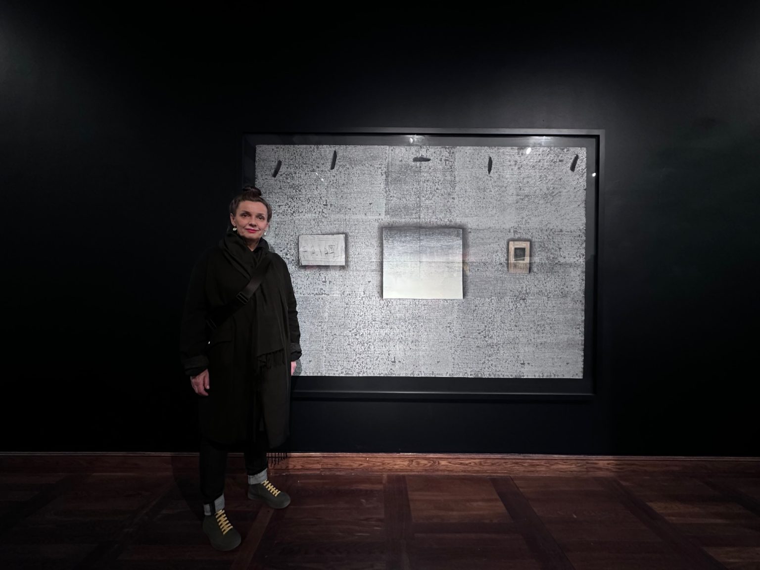 Kobieta stoi przed zawieszonym na ścianie obrazem