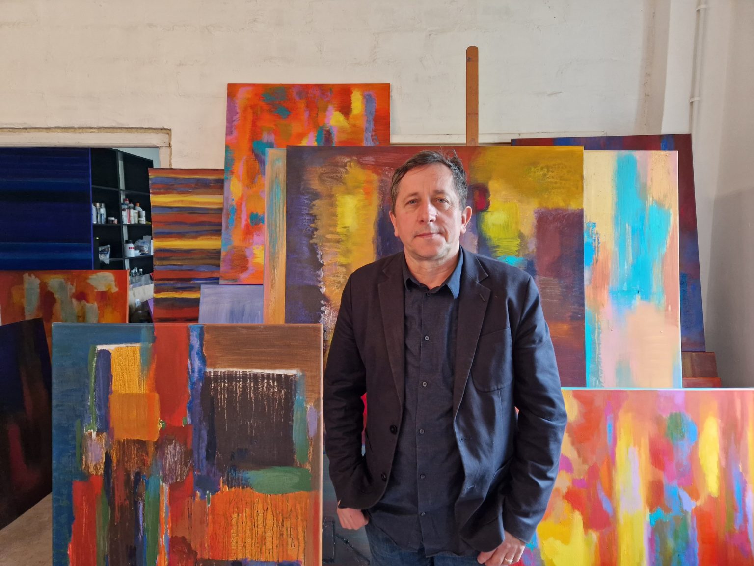 Mężczyzna stoi wśród kolekcji kolorowych obrazów