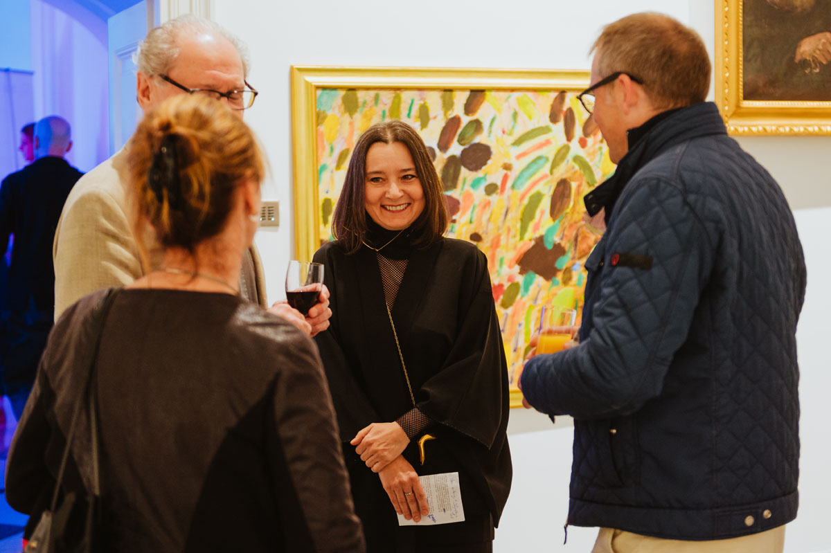 Osoby zwiedzające wystawę na tle obrazu