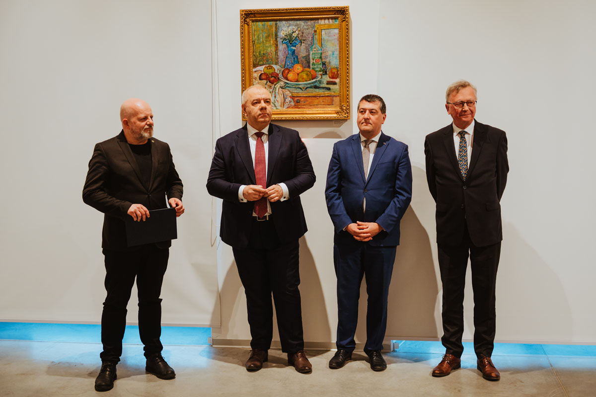 Czterej elegancko ubrani mężczyźni stoją w rzędzie. Obraz w tle