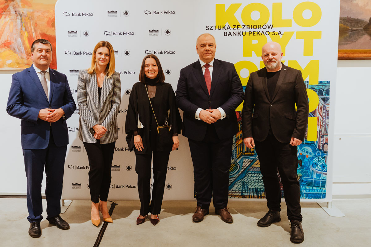 % legancko ubranych osób na tle grafiki z tytułem wystawy