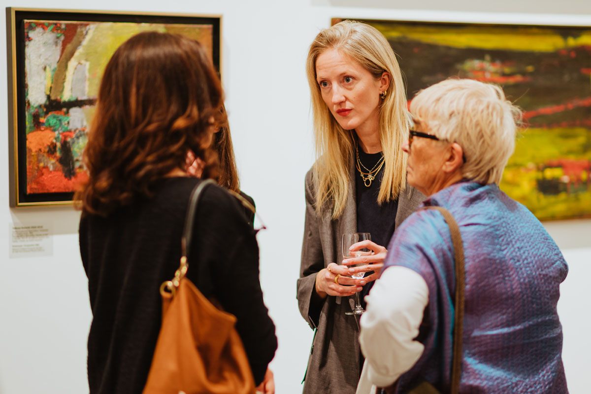 Trzy kobiety rozmawiają w przestrzeni wystawy