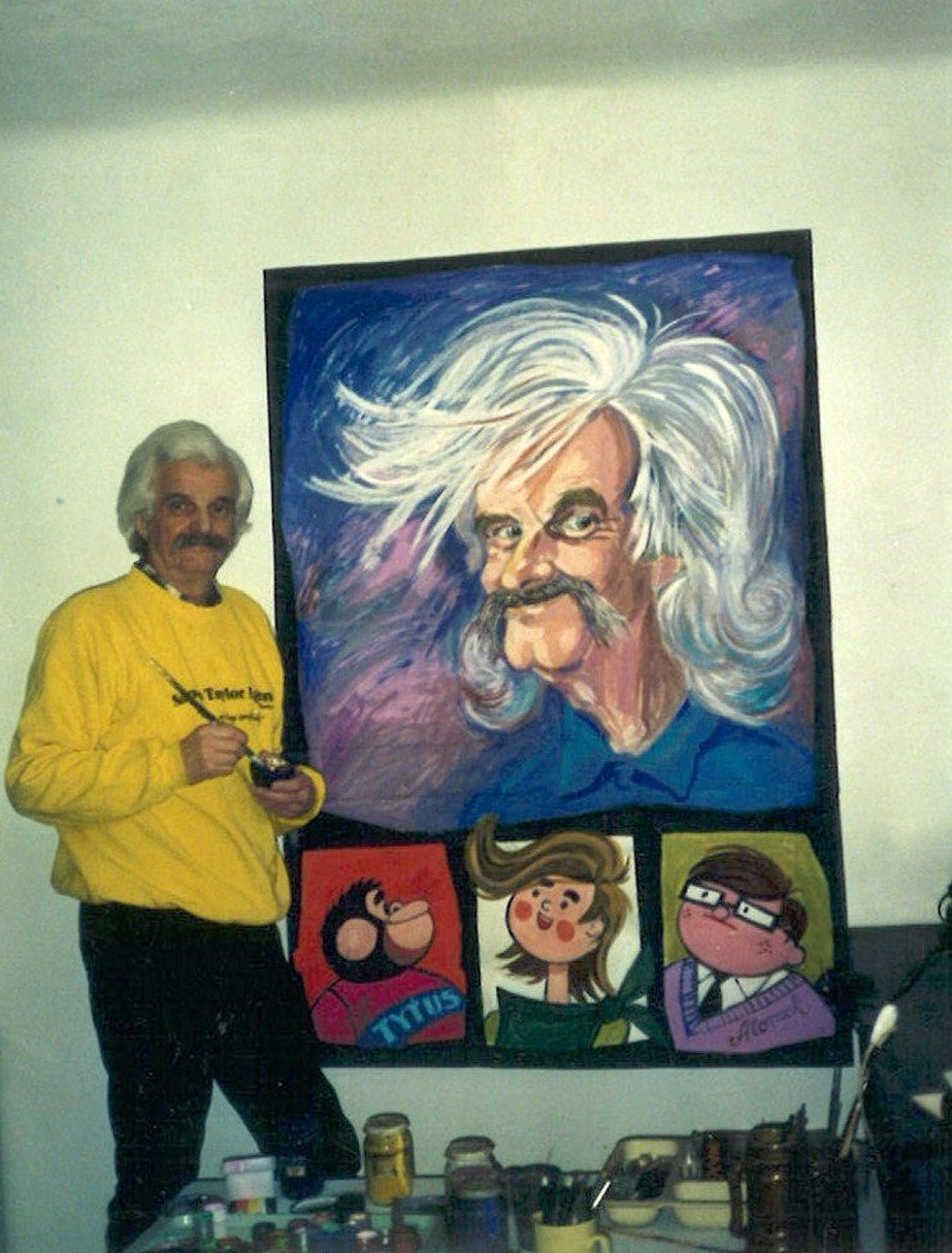 Papcio Chmiel stoi przy ścianie na której wisi jego autoportret. Poniżej portrety głównych bohaterów serii "Tytus, Romek i A`tomek"