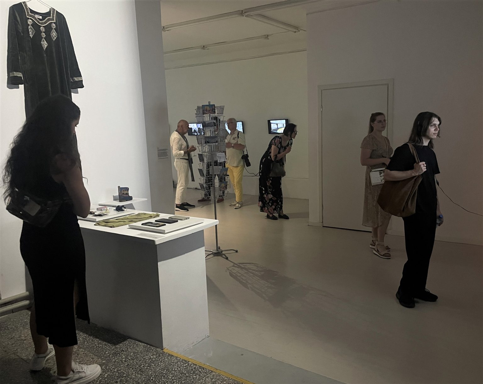 Grupa ludzi w sali wystawowej. Widoczne dzieła sztuki i rzeźby.