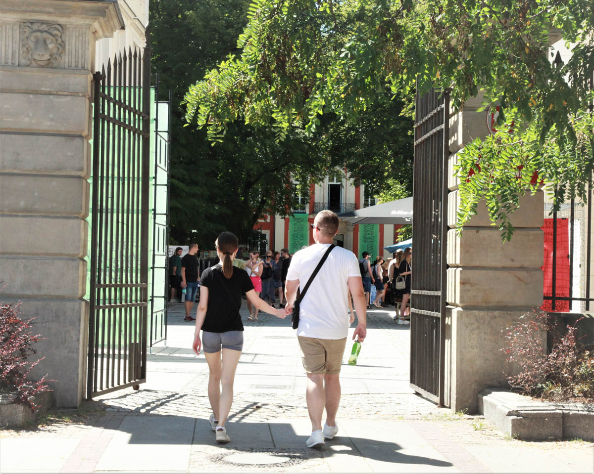 Mężczyzna z dziewczynką wchodzą przez bramę na dziedziniec