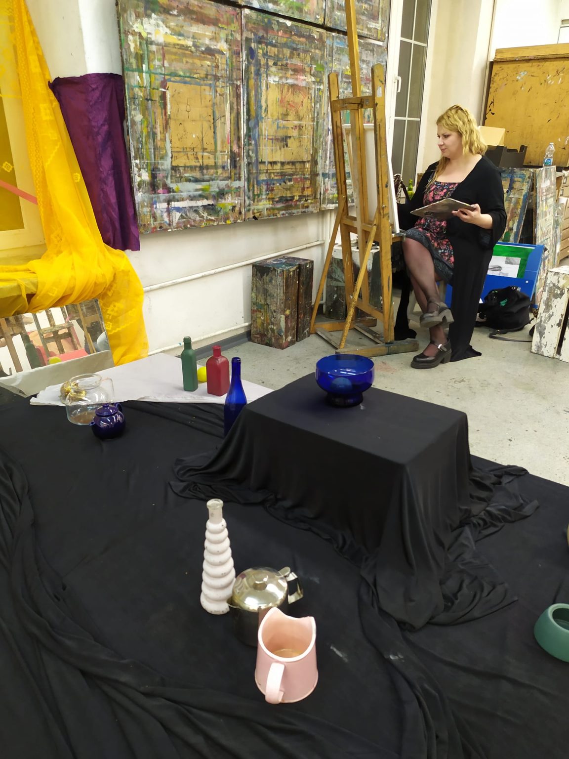 Studentka siedzi przy sztalugach w pracowni.