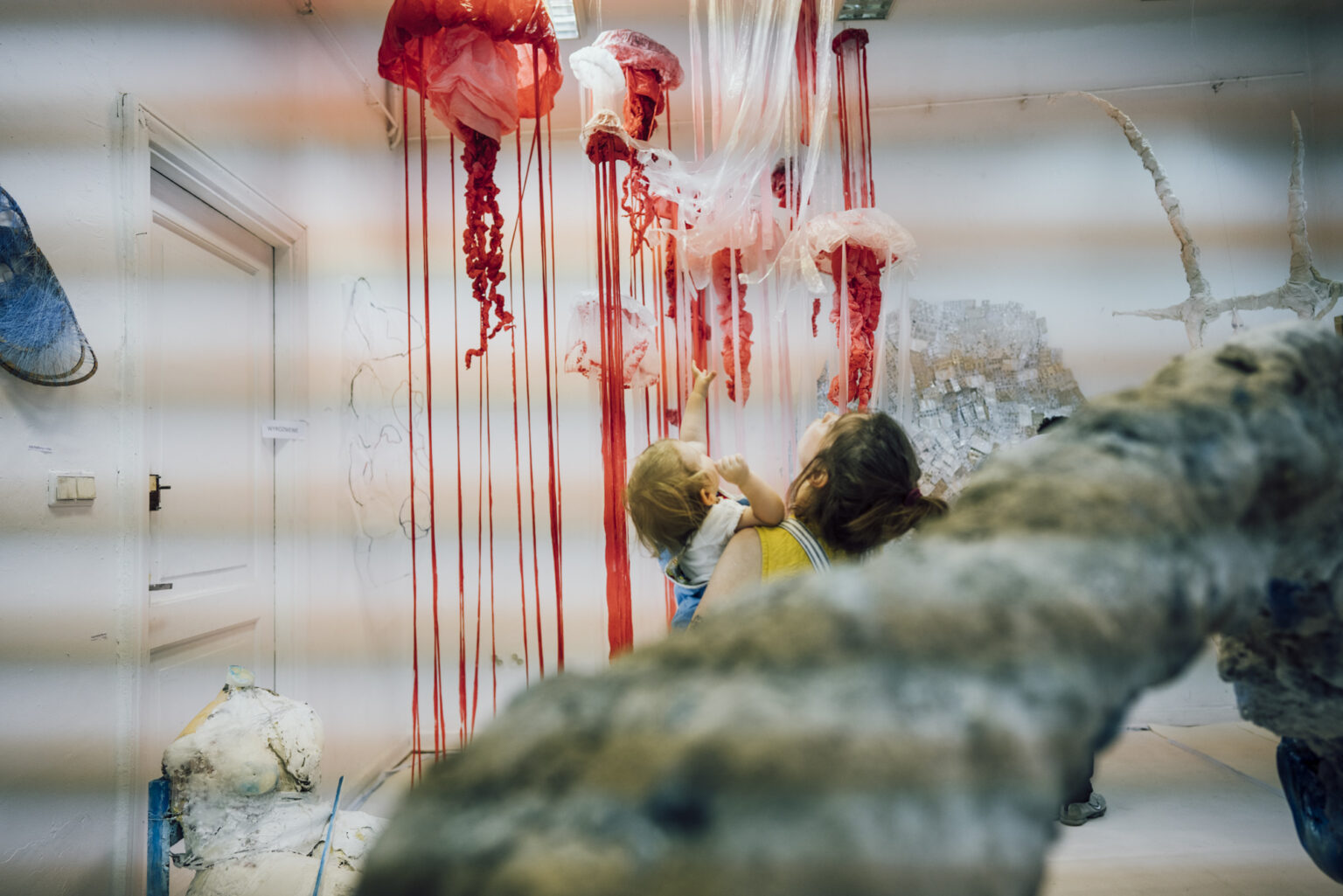 Czerwone ksponaty umocowane do sufitu galerii