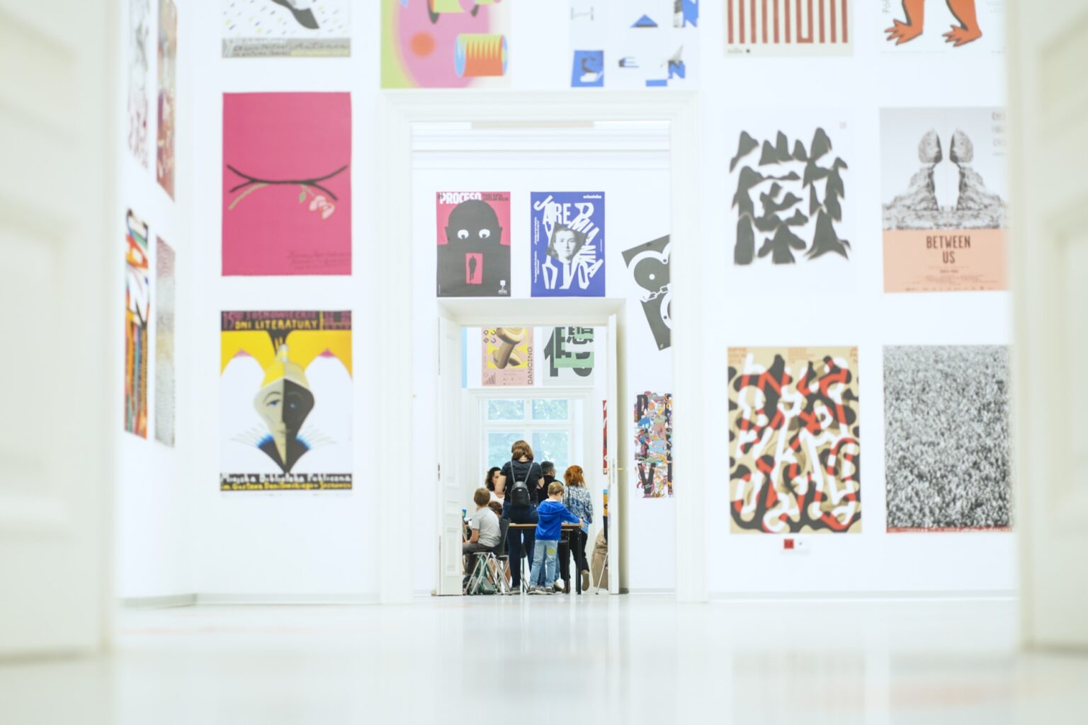 Widok galerii z wystawą plakatów na ścianie.