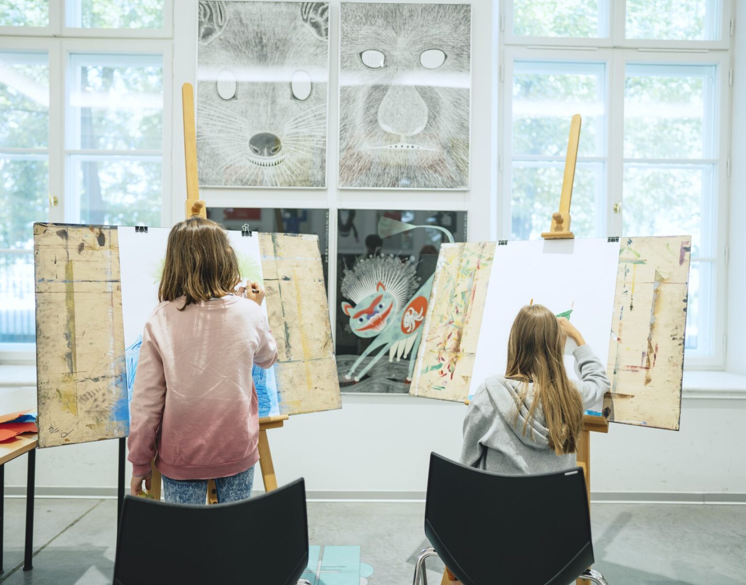 Dwójka dzieci przy sztalugach.