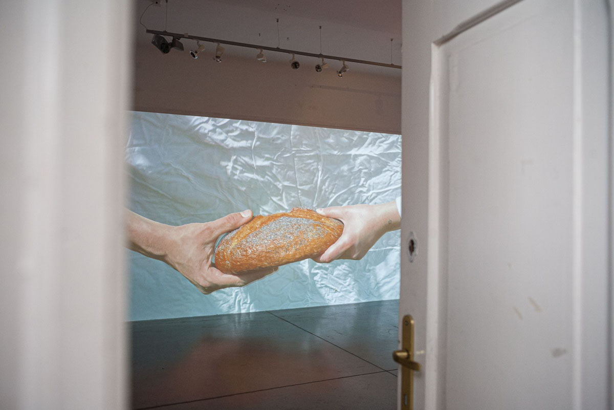 Dłonie dwóch różnych osób trzymające z dwóch stron bochen chleba