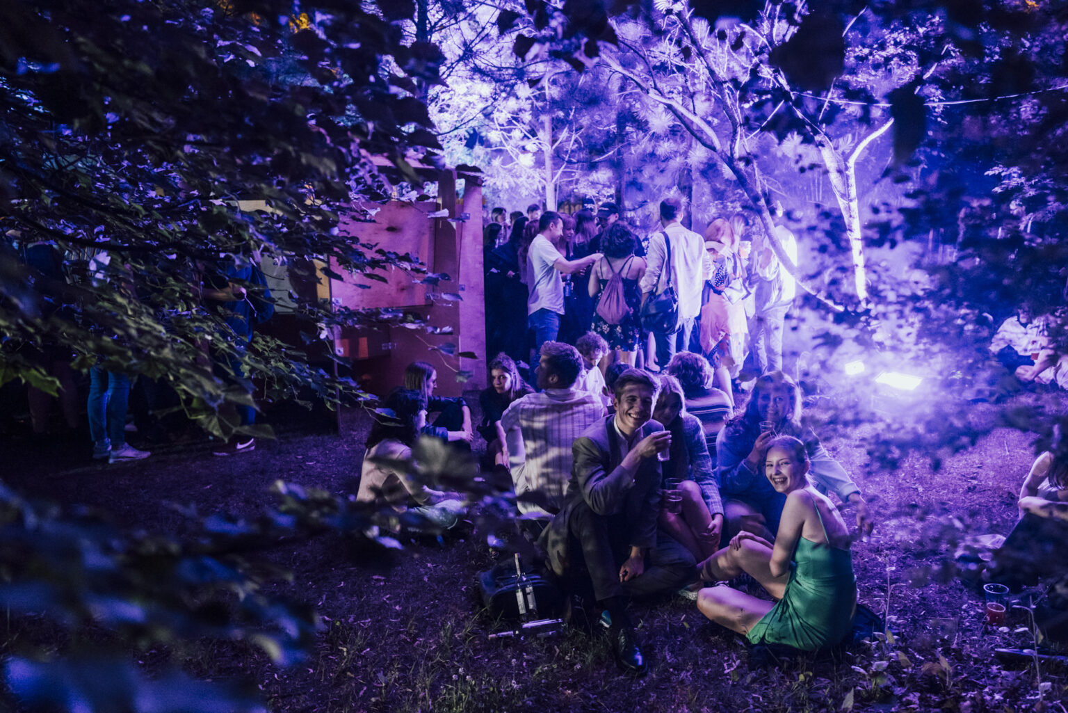 Grupa osób na nocnej imprezie plenerowej wśród drzew