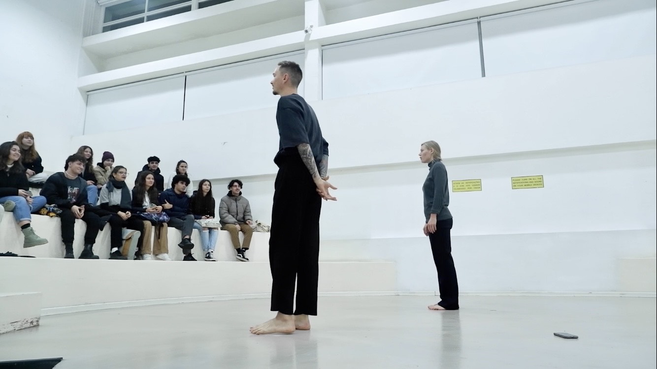 Dwoje ubranych na czarno aktorów stoi twarzami do publiczności