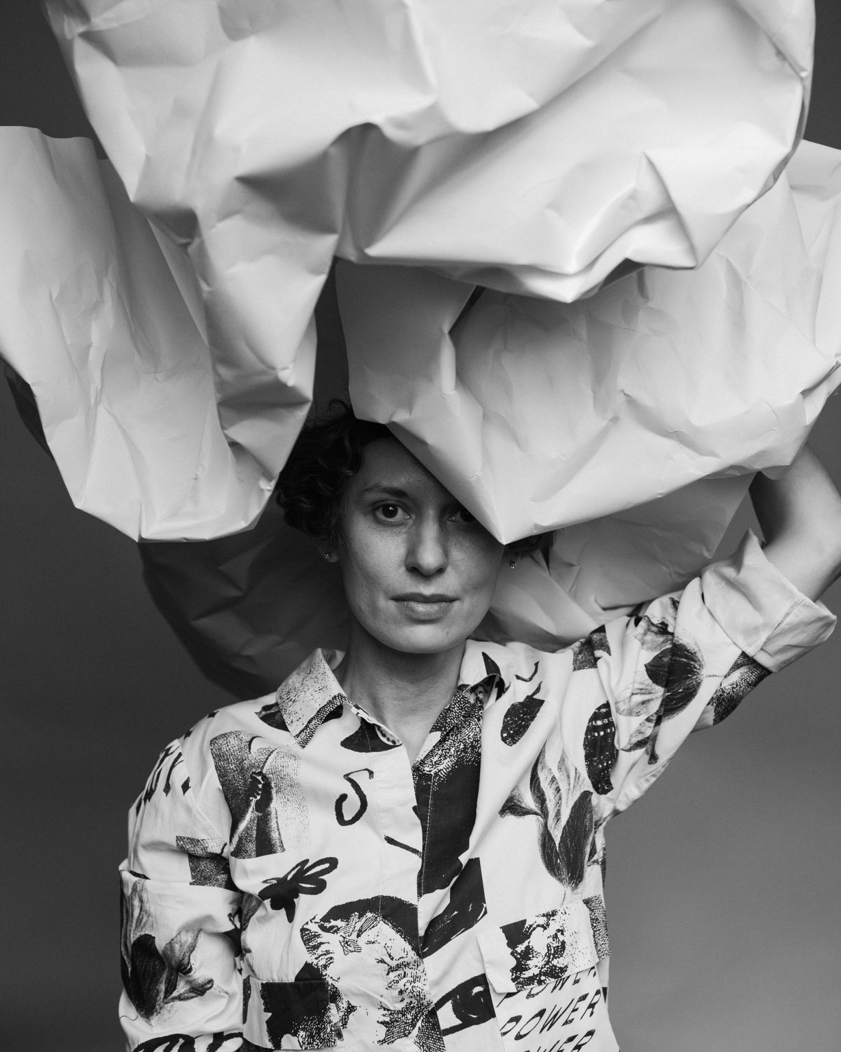 Kobieta ręką trzyma nad głową pognieciony rulon papieru