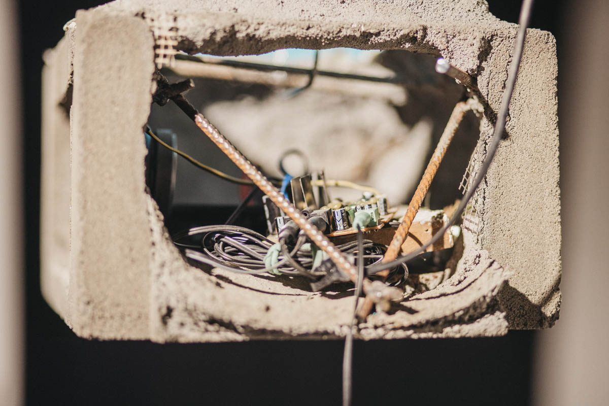 Zbliżenie na leżący w wydrążonym bloku cementu element instalacji elektronicznej