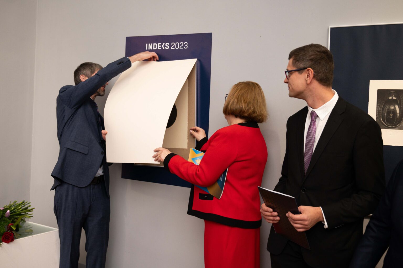 trzy osoby i eksponat na ścianie muzeum