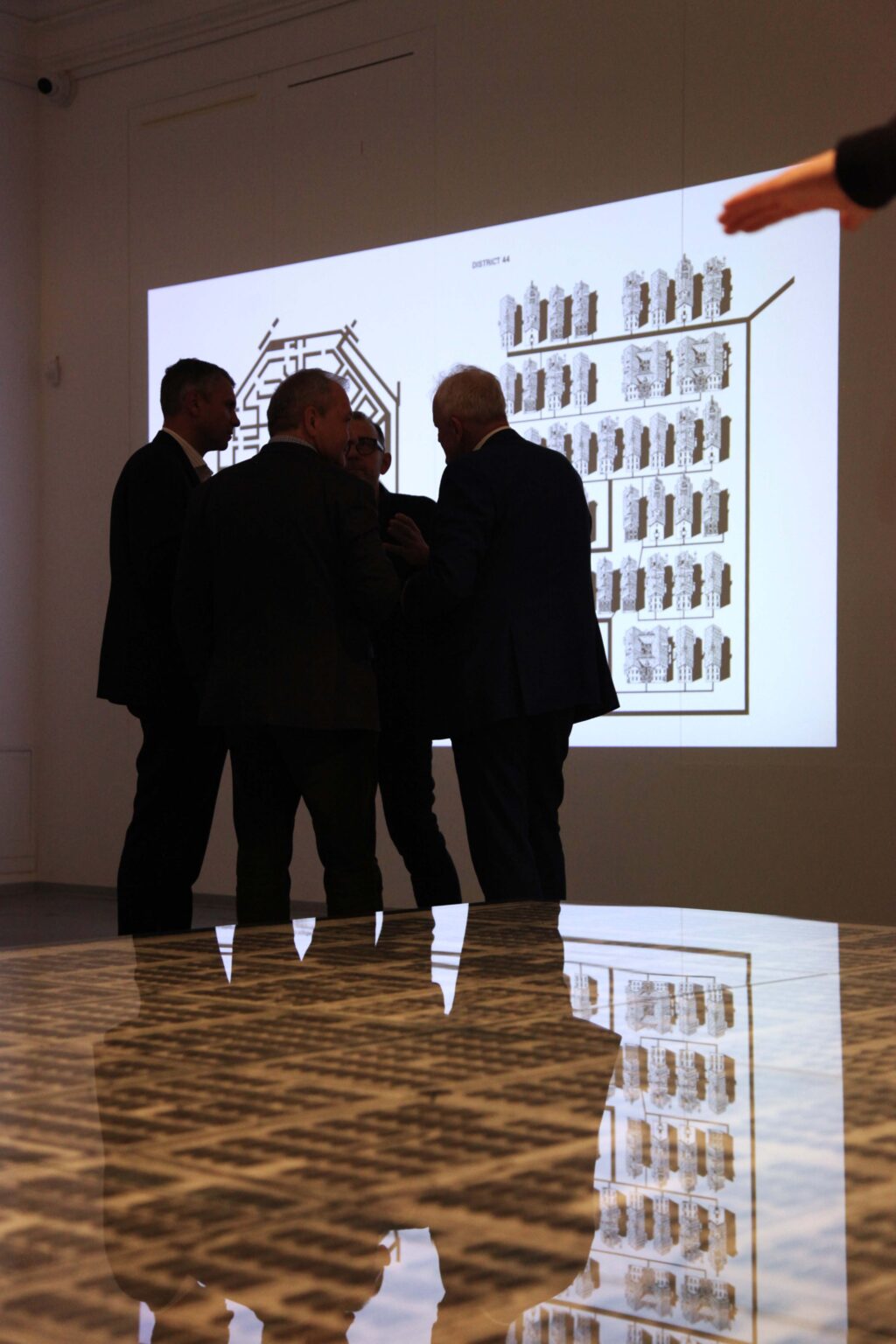 Grupa zwiedzających w przestrzeni wystawowej stoi przed eksponatem