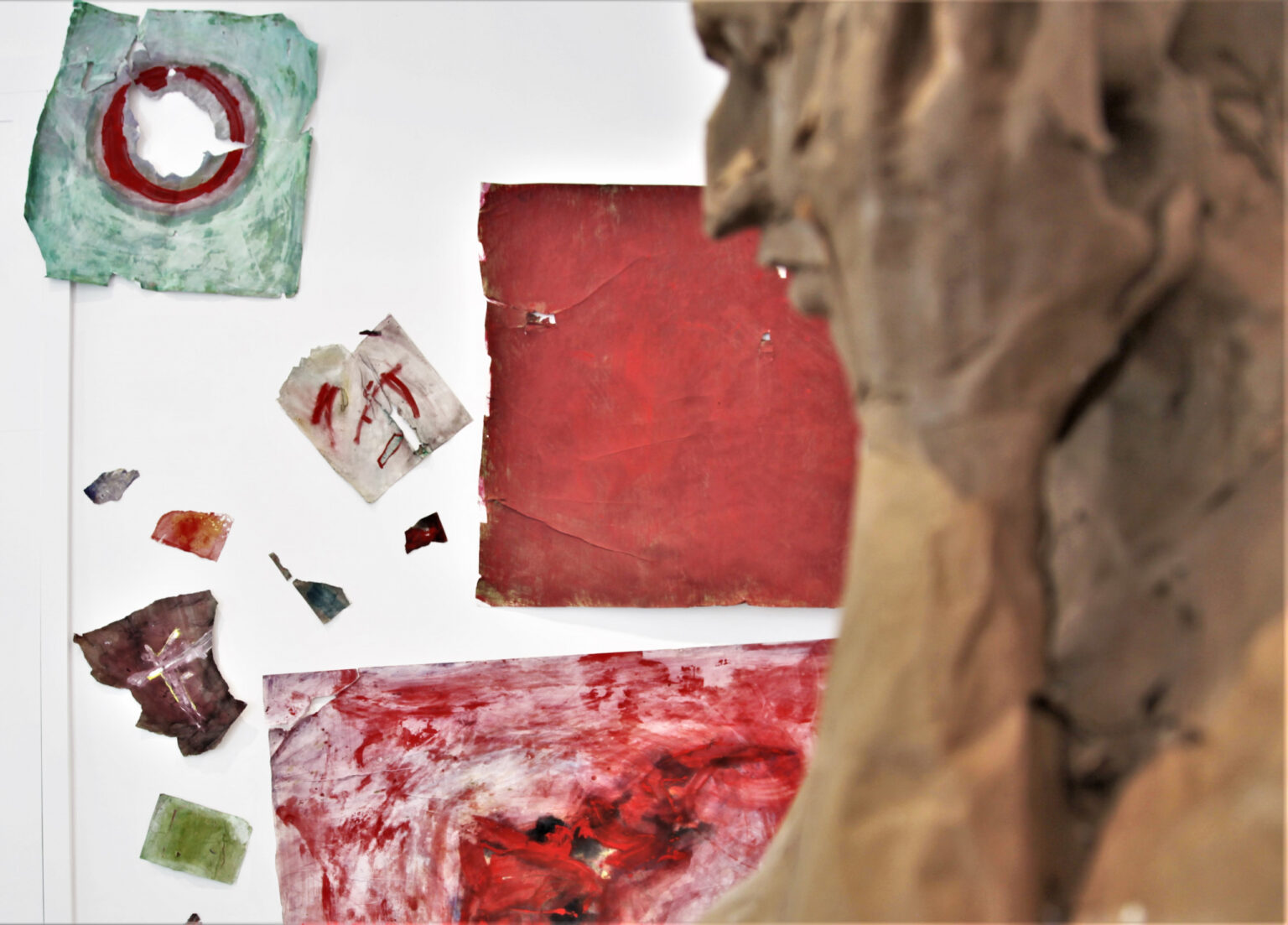 Obrazy widoczne na ścianie częściowo zasłonięte przez stojącą bliżej rzeźbę