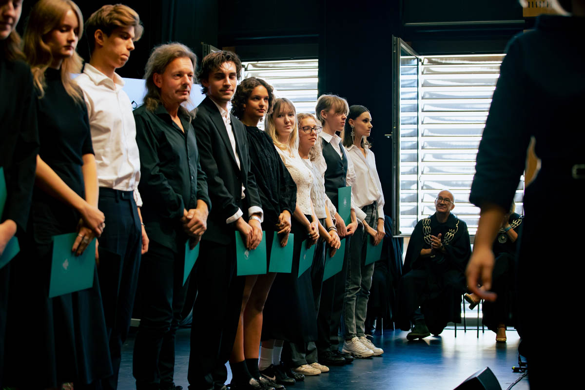 Grupa odświętnie ubranych młodych osób, stojących w rzędzie