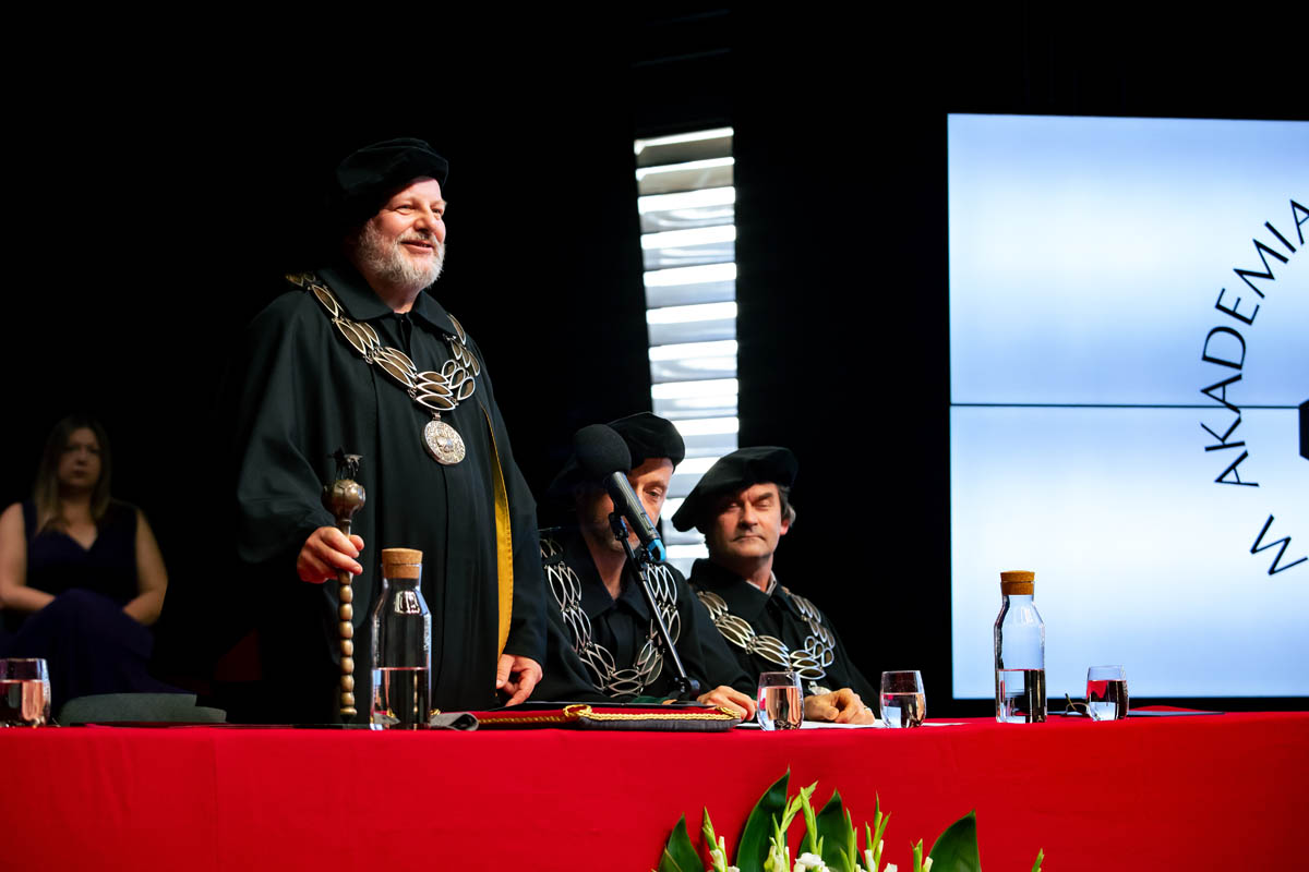 Mężczyzna w uroczystej todze i insygniach akademickich stojący z berłem