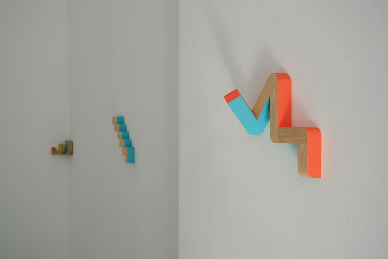 Kolorowe, geometryczne formy przestrzenne na ścianie galerii