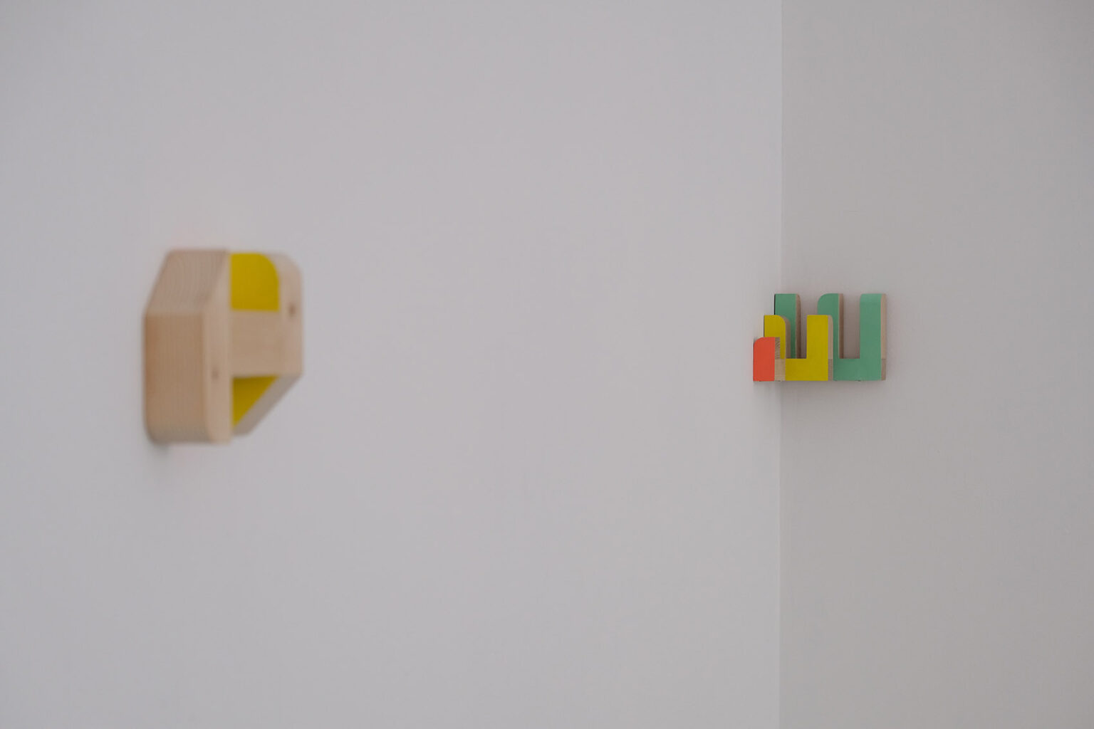 Kolorowe, geometryczne formy przestrzenne na ścianie galerii