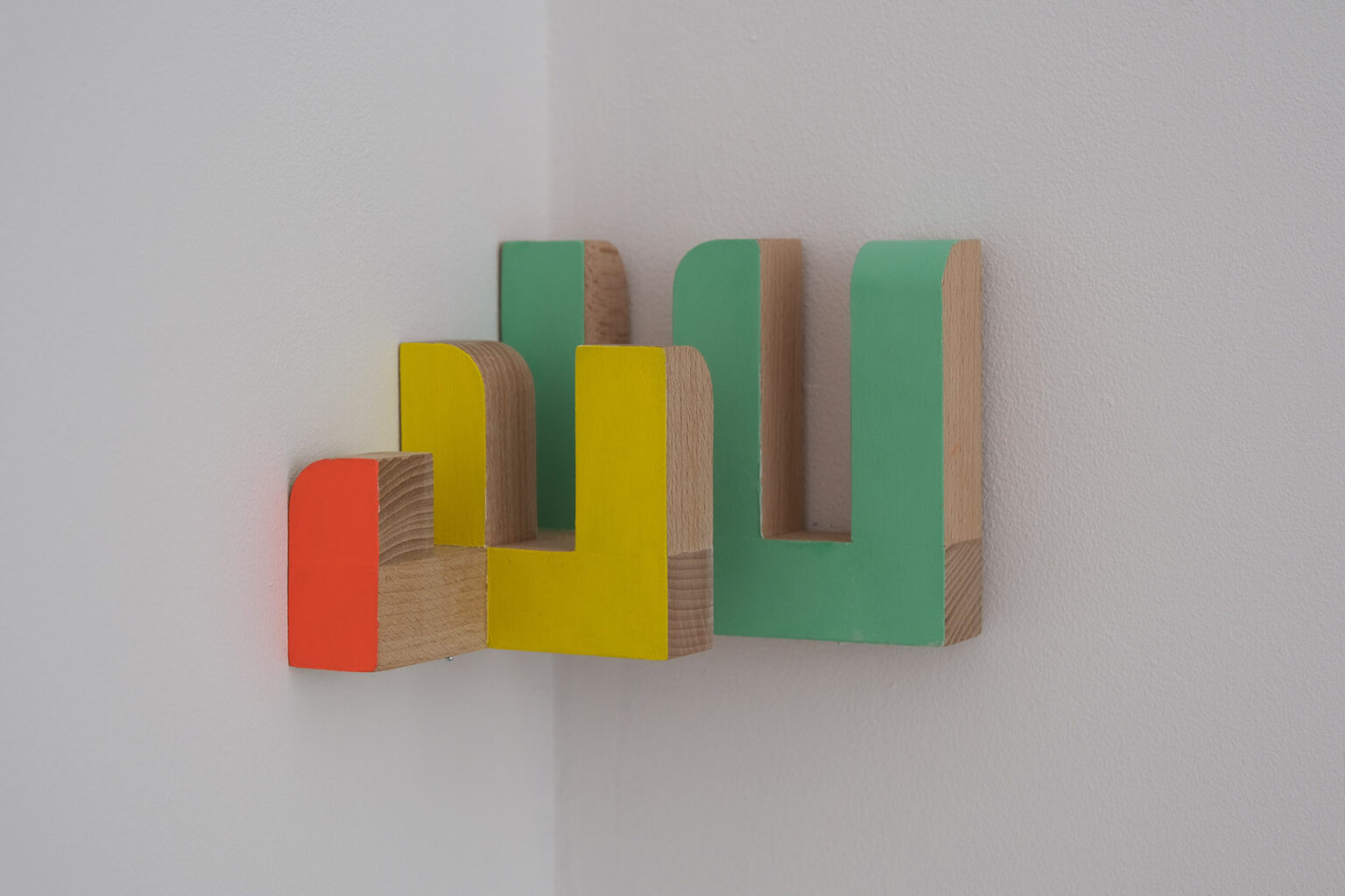 Kolorowe, geometryczne formy przestrzenne na ścianie galerii