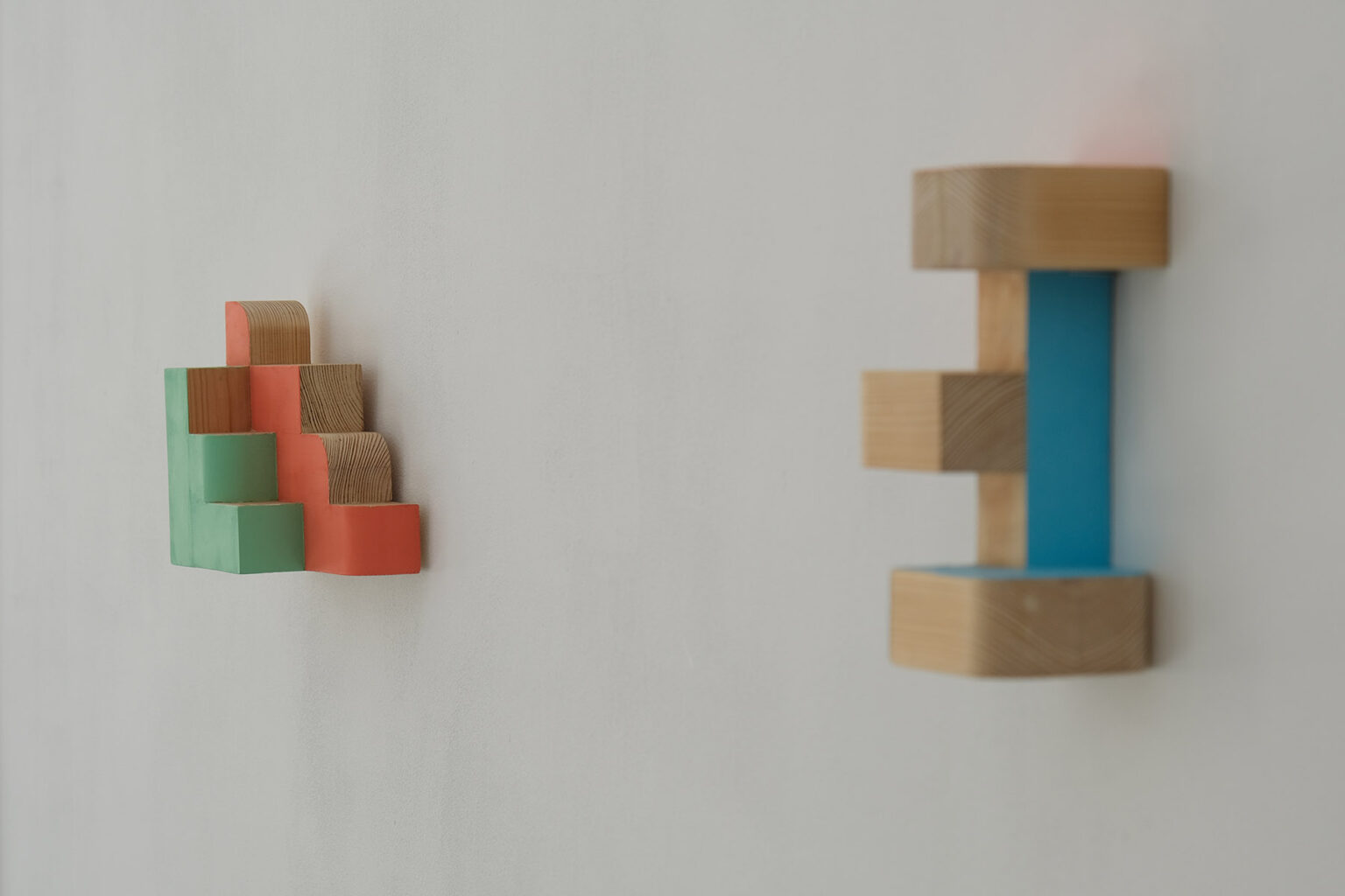 Kolorowe, geometryczne formy przestrzenne na ścianie galerii