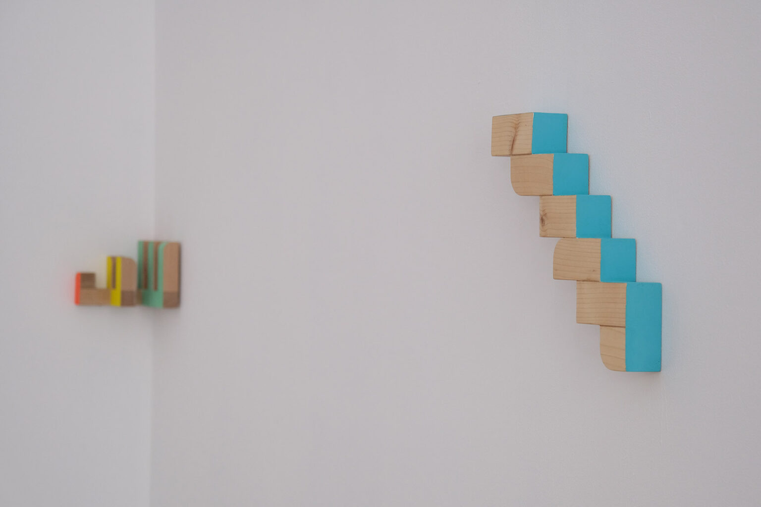 Kolorowe, geometryczne formy przestrzenne na ścianie galerii