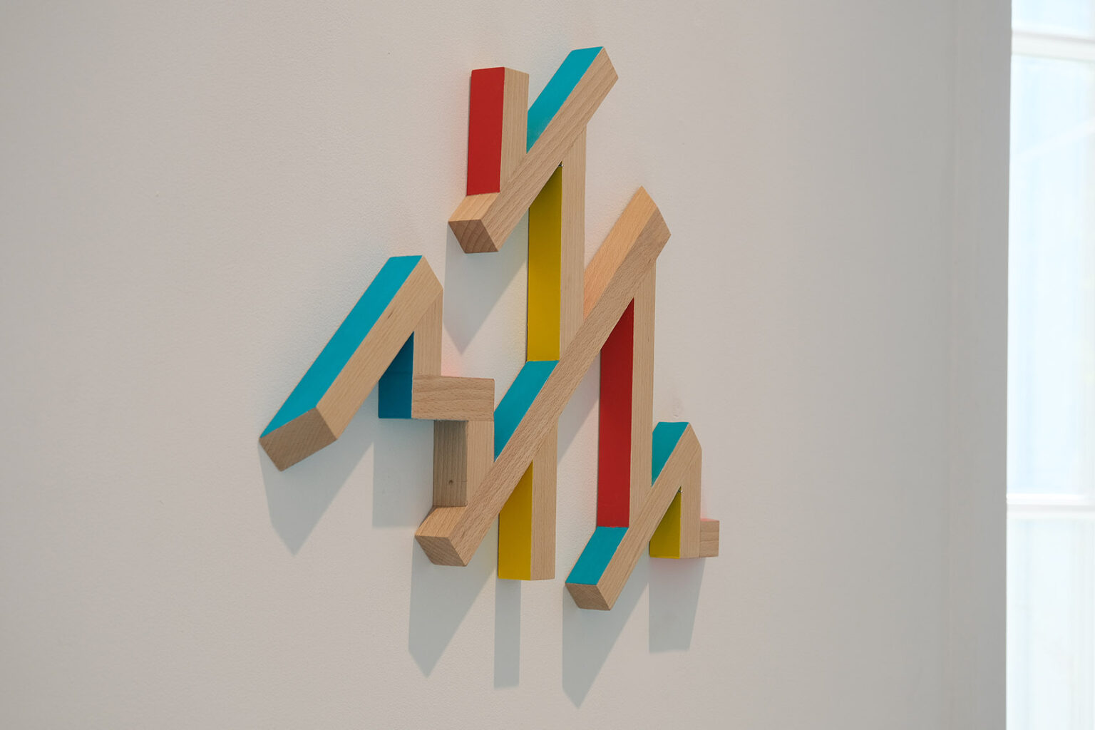Kolorowa, geometryczna forma przestrzenna na ścianie galerii
