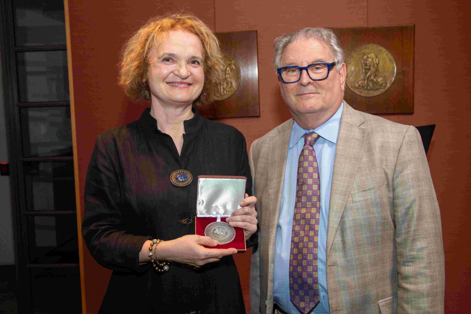 Dwie osoby pozujące do zdjęcia. Kobieta trzyma medal