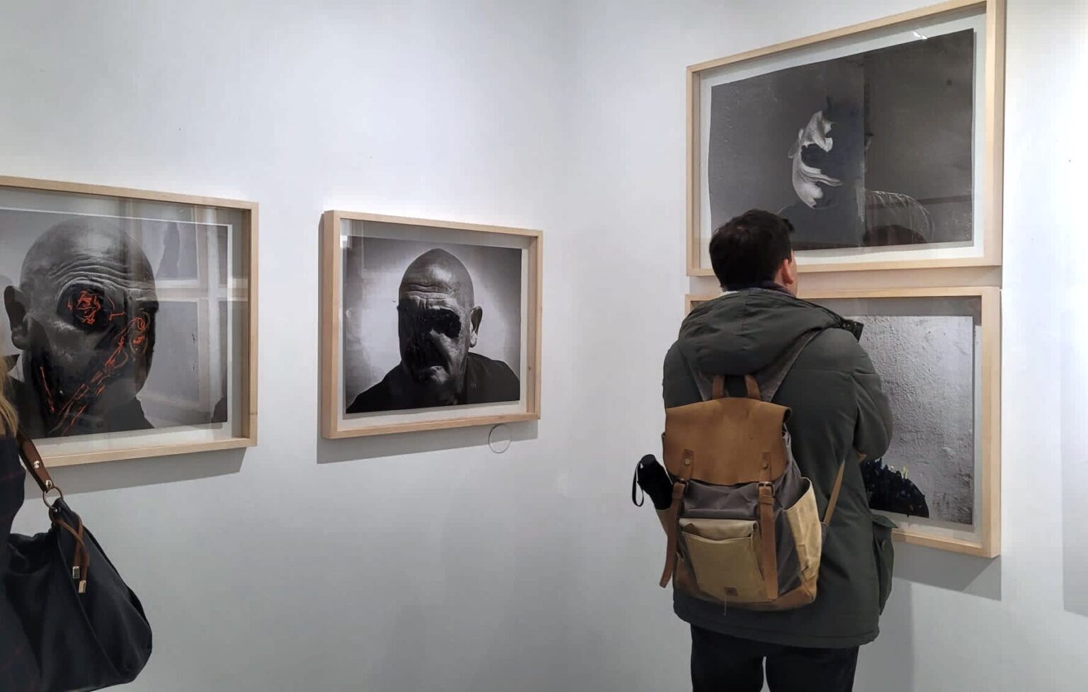 Mężczyzna przygląda sie obrazowi na ścianie galerii