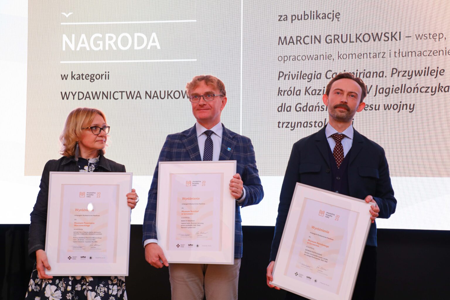 trzy osoby trzymające dyplomy