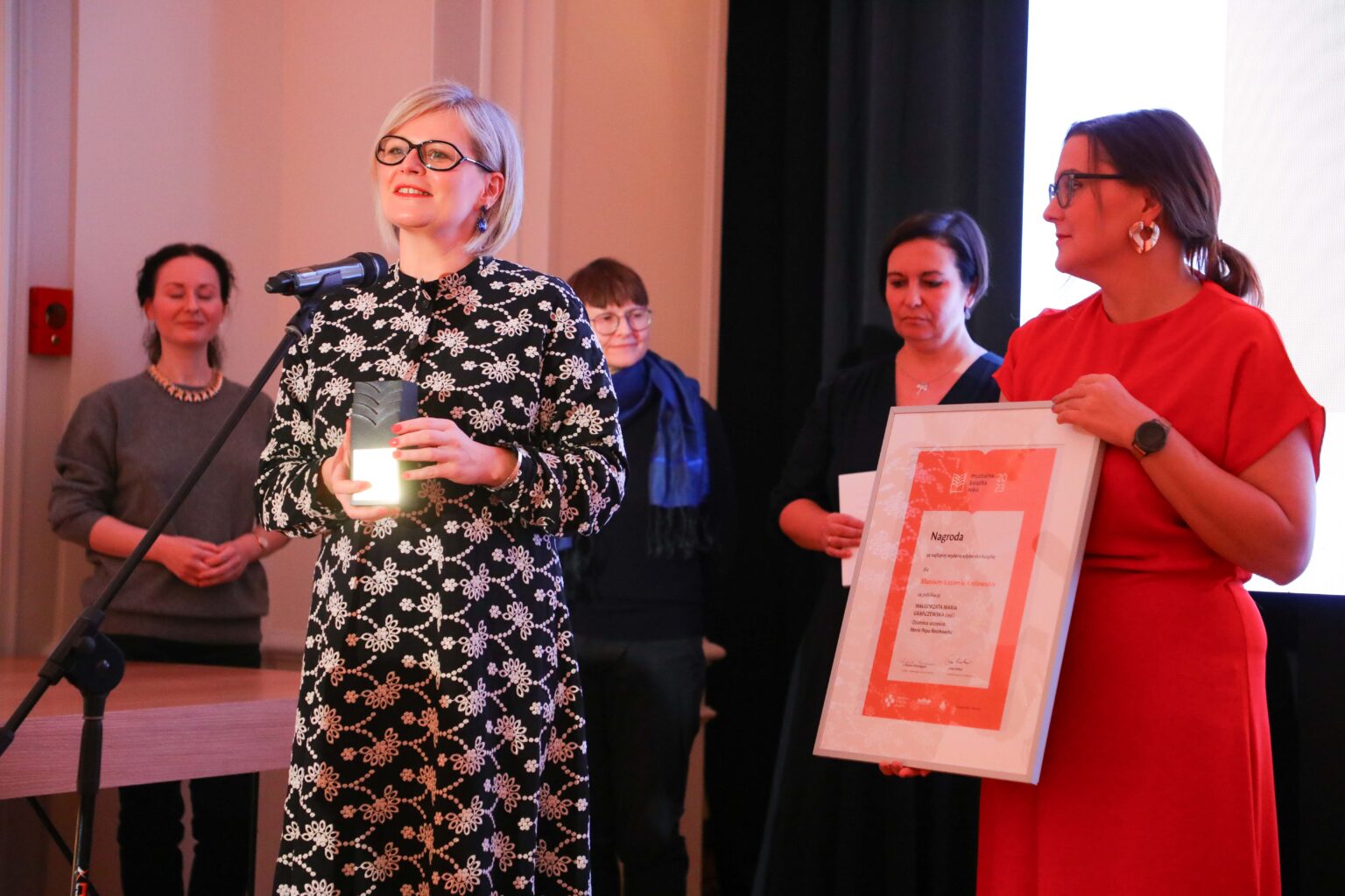 Osoby na scenie odbierają nagrodę