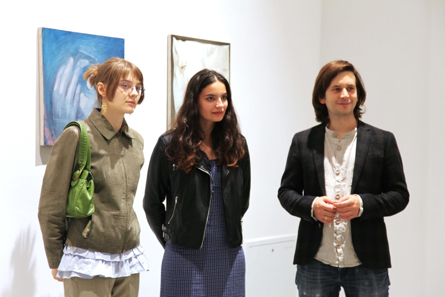 Trzy osoby. Widok wystawy w tle